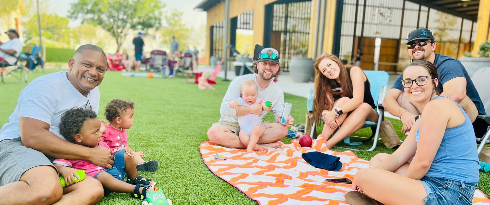 young families with children sitting on the lawn