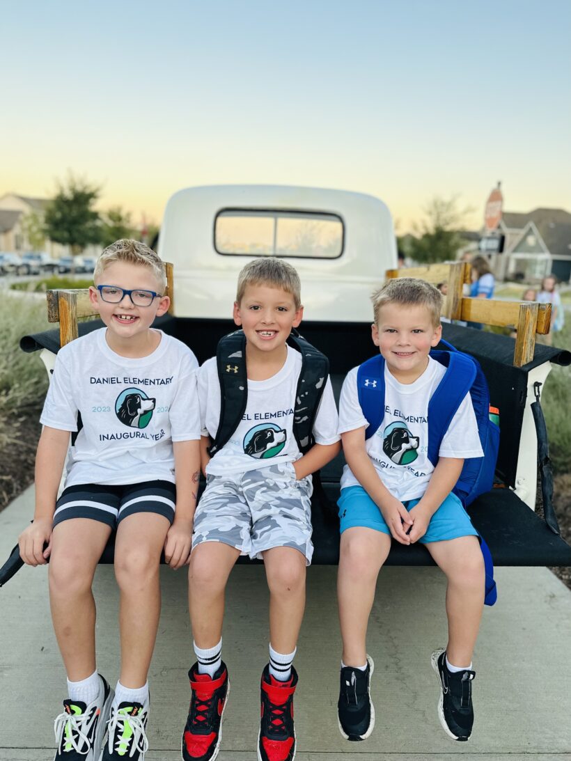 Three school children in the bed of a pickup truck