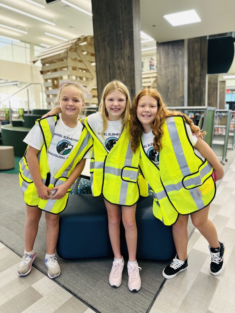 Three school children in safety vests